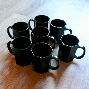 May include: Set of eight black octagonal mugs with handles. The mugs are made of glass and have a smooth, glossy finish.