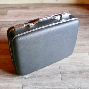 May include: A vintage black suitcase with a silver handle and trim.