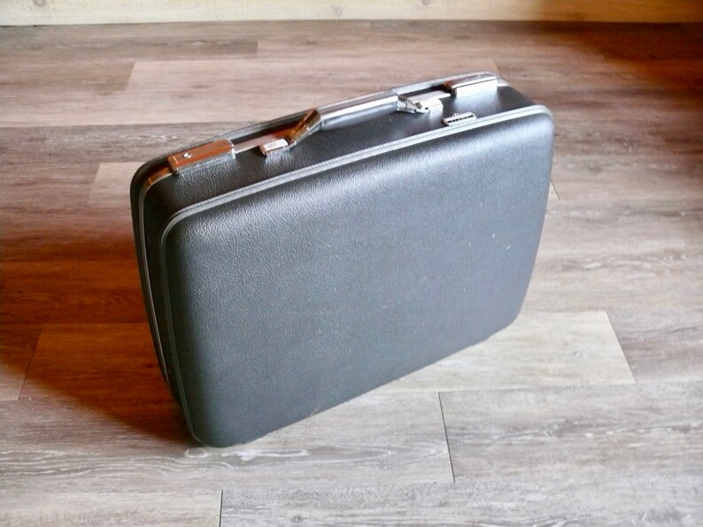May include: A vintage black suitcase with a silver handle and trim.