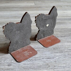 May include: A pair of brown bookends shaped like a rooster. The bookends are made of a textured material and have a brown base.