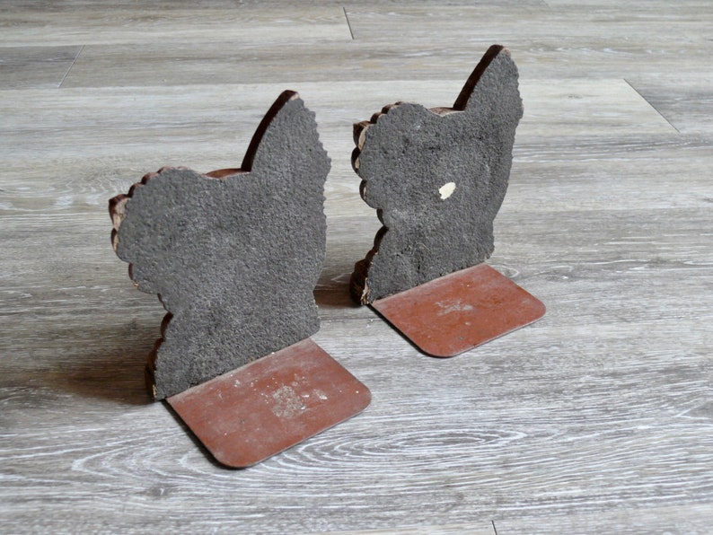 May include: A pair of brown bookends shaped like a rooster. The bookends are made of a textured material and have a brown base.
