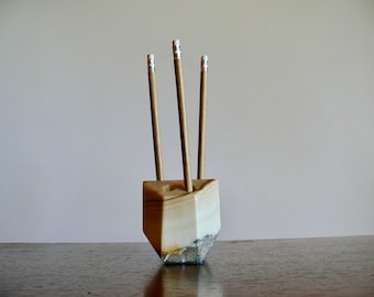 May include: A white marble pencil holder with a geometric shape and three pencils inside.