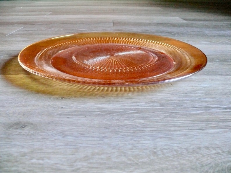 Puede incluir: Un plato de servir de vidrio &aacute;mbar transparente con un patr&oacute;n decorativo de c&iacute;rculos conc&eacute;ntricos.