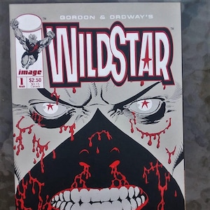 May include: A comic book cover featuring a close-up of a monstrous face with a black mask and red blood dripping down. The title "WILDSTAR" is in white letters with a red star. The comic book is published by Image Comics.