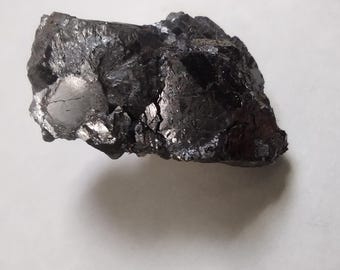 May include: A large, dark gray, irregularly shaped rock with a rough, textured surface.