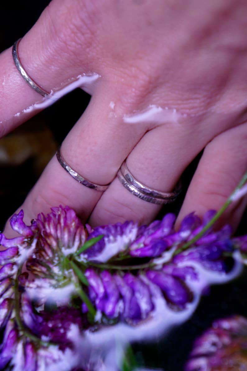 Peut inclure: Deux anneaux en argent sur un doigt, avec une fleur violette en arri&egrave;re-plan.