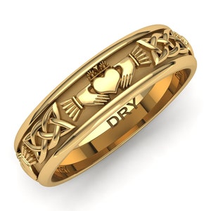 May include: A gold Celtic knot wedding band with a Claddagh design featuring two hands holding a heart with a crown on top. The band is engraved with the word "DRY".