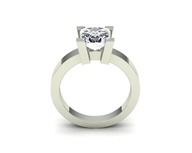 May include: A silver ring with a large, clear, square-shaped diamond set in a simple, modern design.