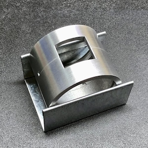 May include: A silver-colored metal clamp with a square cutout in the center. The clamp is attached to a rectangular base. The object is made of a shiny, industrial-looking metal.