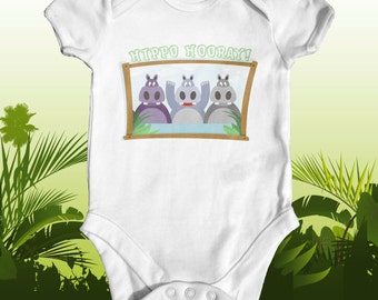 May include: White baby onesie with a picture of three hippos in a window frame. The text "HIPPO HOORAY!" is above the frame.