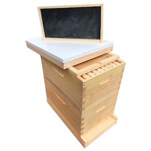 May include: A wooden beehive with a white top and a black plastic frame. The beehive is made of natural wood and has a simple design.