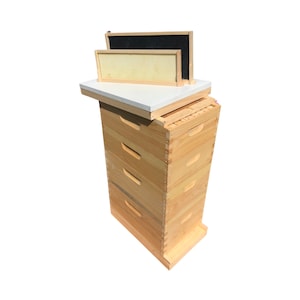 May include: A wooden beehive with five boxes stacked on top of each other. The top box has a white lid and two frames on top of it. The frames are made of wood and have a black and yellow honeycomb pattern.