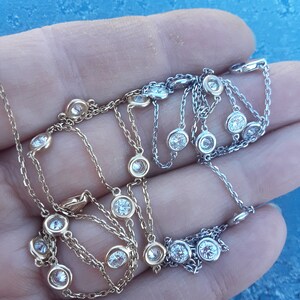 May include: Two delicate necklaces with small round diamonds on a chain. One necklace is gold and the other is silver.