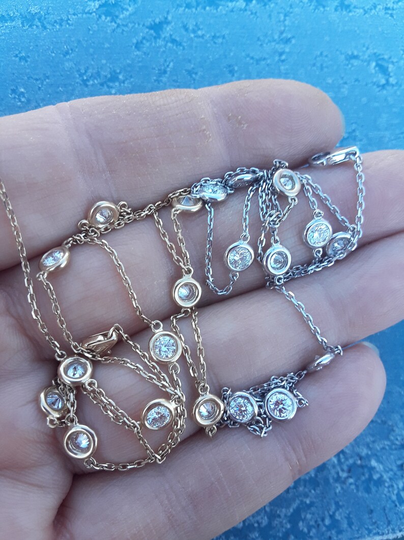 May include: Two delicate necklaces with small round diamonds on a chain. One necklace is gold and the other is silver.