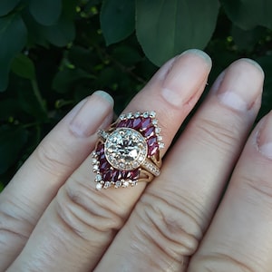 May include: A gold ring with a large round diamond surrounded by smaller diamonds and a halo of red rubies.