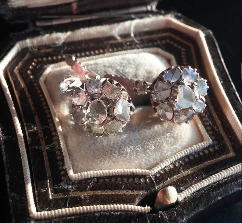 May include: A pair of antique diamond earrings with a cluster of rose cut diamonds set in silver. The earrings are in a vintage jewellery box.