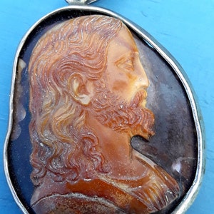 May include: A silver pendant with a cameo of a man's face carved from amber. The cameo is set in a silver frame and the pendant has a silver bail.