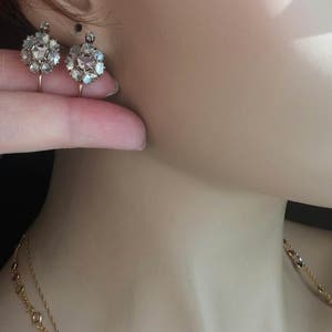 May include: A pair of antique gold earrings with a cluster of rose cut diamonds. The earrings are on a mannequin's ear.