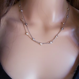 May include: A delicate silver and gold chain necklace with small round clear stones.