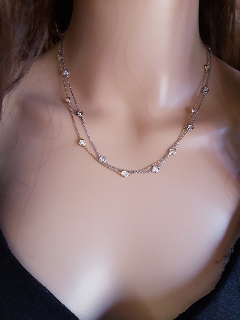 May include: A delicate silver and gold chain necklace with small round clear stones.