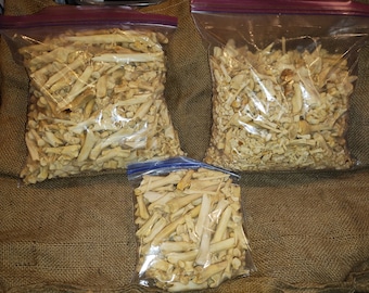 May include: Three bags of white animal bones, likely chicken bones, in various sizes. The bones are in clear plastic bags with zipper closures. The bags are sitting on a brown burlap surface.
