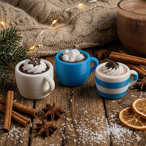 May include: Three miniature mugs of hot chocolate with whipped cream and toppings, including marshmallows and chocolate shavings. The mugs are white, blue, and blue-and-white striped. Cinnamon sticks, star anise, and orange slices are scattered around the mugs on a wooden surface.