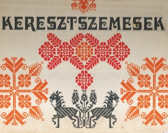 Peut inclure: Une couverture de livre vintage avec le titre "KERESZTSZEMESEK" en texte noir. La couverture présente un motif de point de croix rouge et orange avec des motifs floraux stylisés et deux chevaux noirs stylisés.