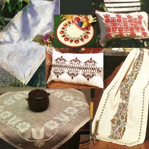 Op de afbeelding: Een verzameling witte linnen tafelkleden en kussenslopen met ingewikkelde borduurmotieven. De ontwerpen omvatten bloemmotieven, geometrische patronen en traditionele volkskunst. De linnen worden getoond op een houten tafel en een stoel.