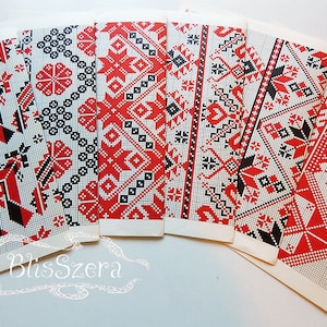 May include: A selection of rectangular cards displaying detailed red, black, and white geometric patterns. The designs include floral and star motifs, set against a grid background. The cards are fanned out, highlighting the diverse patterns.