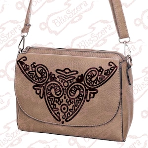 May include: A tan-coloured crossbody bag with a flap closure and a decorative dark brown design. The bag has a long, adjustable strap and silver-tone hardware. The design on the flap features a symmetrical, ornate pattern.