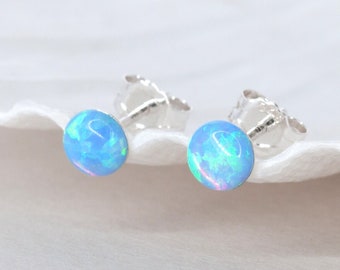 May include: A pair of silver stud earrings with light blue opal gemstones.