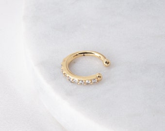 Può includere: Un orecchino a cerchio in oro con una fila di pietre di zircone cubico trasparenti.