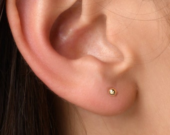 Puede incluir: Primer plano de una oreja con un pequeño pendiente de bola de oro.