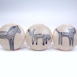 May include: Three round, cream-colored fabric buttons with a gray horse, fox, and cat design.