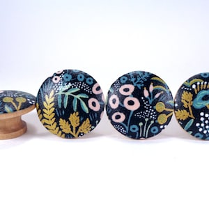 May include: Four wooden knobs with a black background and a floral pattern in shades of pink, blue, green, and gold.