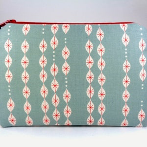 May include: A light blue zippered pouch with a red zipper and a white and red geometric pattern.