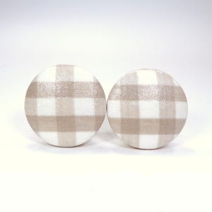 May include: A pair of round, beige and white gingham fabric earrings.