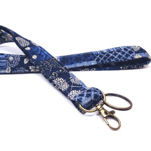 May include: A blue and white patterned fabric lanyard with a gold metal key ring.