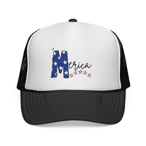 Może przedstawiać: Biało-czarna czapka typu trucker z grafiką na przednim panelu. Wzór zawiera dużą niebieską literę M wypełnioną białymi gwiazdkami, po której następuje czarny kursywny napis erica oraz rząd małych czerwonych i niebieskich konturów gwiazd.