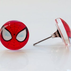 以下が含まれることがあります： スパイダーマンの顔のデザインが施された赤と白のスタッドピアスのペア
