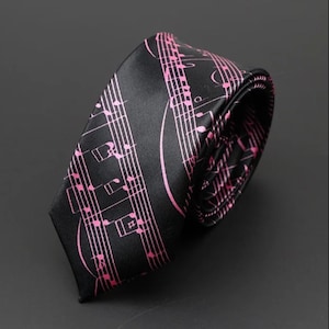Könnte beinhalten: Schwarze Krawatte mit einem sich wiederholenden Muster aus rosa Noten. Die Krawatte ist aus glänzendem Stoff gefertigt und aufgerollt, wodurch das Innenfutter mit dem gleichen Notenmuster sichtbar wird.