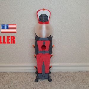 Peut inclure: Objet décoratif de couleur rouge et grise, avec une section centrale transparente et bulbeuse. Il possède un sommet en forme de couronne et une base avec de petits pieds. Les mots "US SELLER" et un drapeau américain sont visibles.