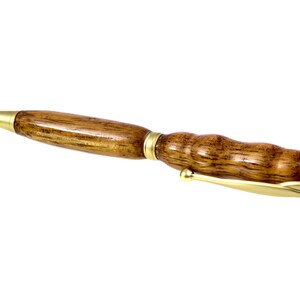 May include: A wooden pen with a gold-colored tip and a gold-colored band around the barrel.