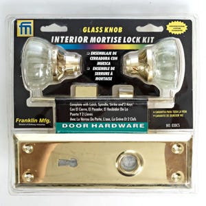 May include: An interior mortise lock kit by Franklin Mfg. in clear plastic packaging. Includes two clear glass knobs with brass bases, a brass rectangular faceplate with a keyhole and knob opening, a latch, spindle, strike, and two keys. No. 030CS.