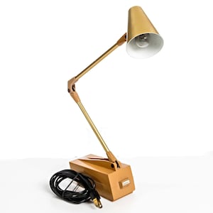 May include: A white ceramic mug with a black handle and the text "But First, Coffee" in a bold, black font. The mug is set against a blurred background, suggesting a cozy setting.