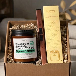 May include: A candle and lighter set in a cardboard box. The candle is in a glass jar with a black lid, labeled "The Calming Scent of a Color Coded Spreadsheet." A copper-colored electric lighter and a yellow candle lighter box are also included.