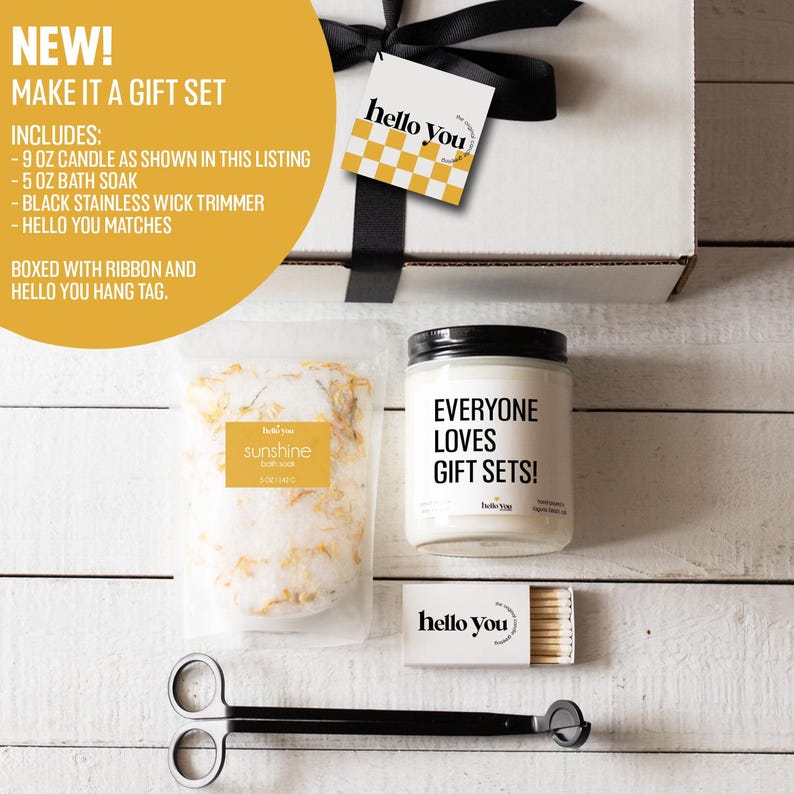May include: A gift set includes a 9 ounce candle with the text "Everyone Loves Gift Sets!" and a 5 ounce bath soak labeled "sunshine bath soak". The set also includes a black wick trimmer, matches, and a black and white "hello you" hang tag.