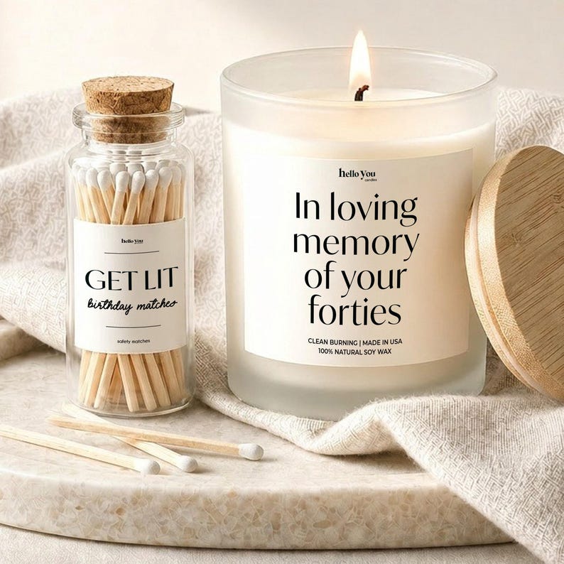 a candle and a matchbox, both with a label that reads "In loving memory of your forties".