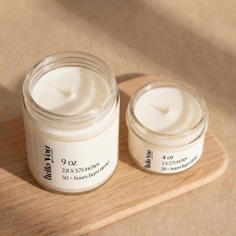 Two candles in glass jars, one larger and one smaller, placed on a wooden surface.