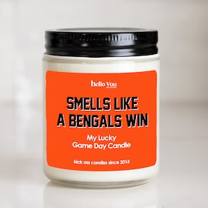 May include: Orange and black candle jar with the text "Smells like a Bengals win" and "My Lucky Game Day Candle". The text "kick ass candles since 2015" is at the bottom of the label.